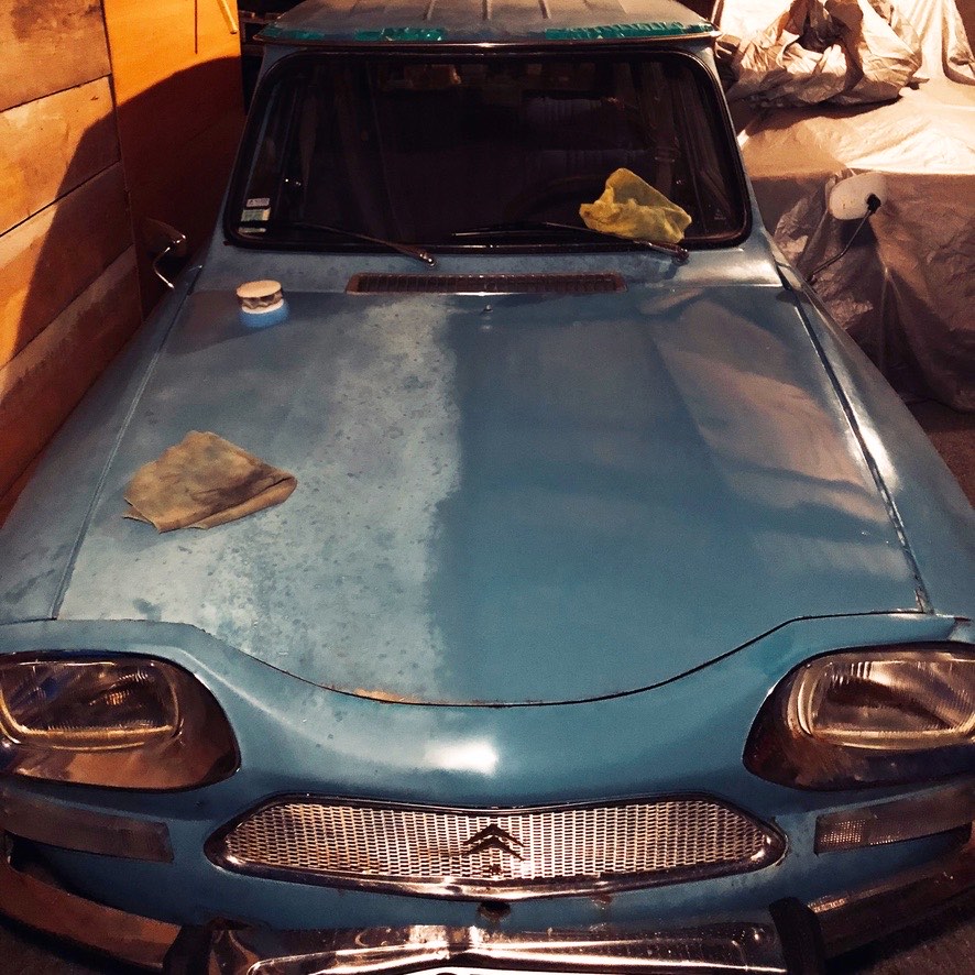 Capot d'une Citroën Ami 8 bleue pendant un lustrage, avec la différence de brillance visible
